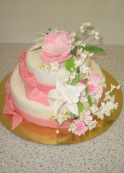 Двухъярусный белый свадебный торт с букетом из лилий, орхидей с розовыми бантами